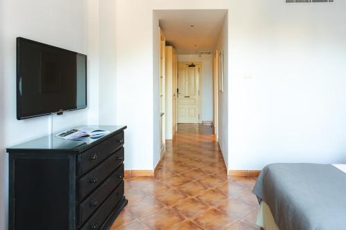 a bedroom with a dresser with a flat screen tv on it at Ona Lomas Village - La Manga Club in La Manga del Mar Menor