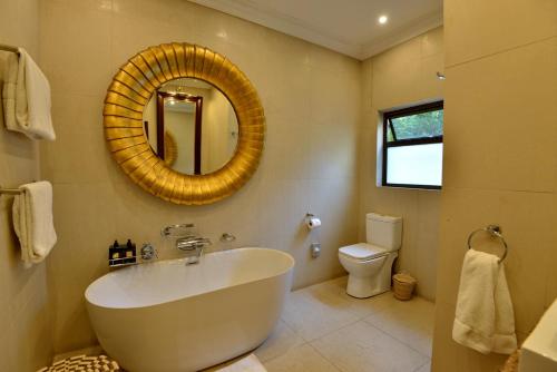 a bathroom with a tub and a toilet and a mirror at The Residence in Johannesburg