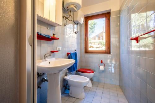 a bathroom with a sink and a toilet and a window at Villetta Panoramica Costa Paradiso in Costa Paradiso
