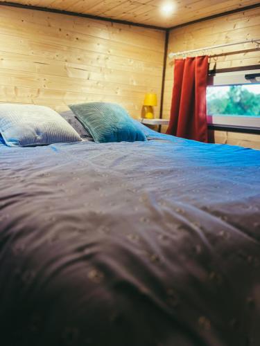 - un lit avec des draps et des oreillers bleus dans l'établissement Le Jardin d'Emilie TINY, à Menetou-Râtel