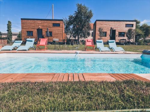 a swimming pool with chairs and a house in the background at Le Jardin d'Emilie TINY in Menetou-Râtel