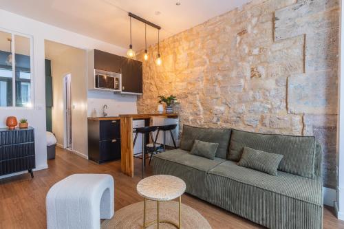 un salon avec un canapé et un mur en pierre dans l'établissement Île SAINT LOUIS, NOTRE DAME, suite 1 chambre 2 à 4p, à Paris
