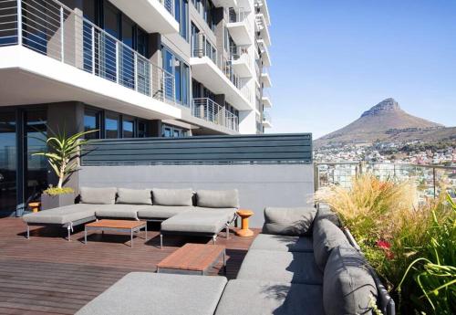 a patio with couches and tables and a building at Modern 14th floor Apt with Balcony & Mountain Views at 16onBree in Cape Town