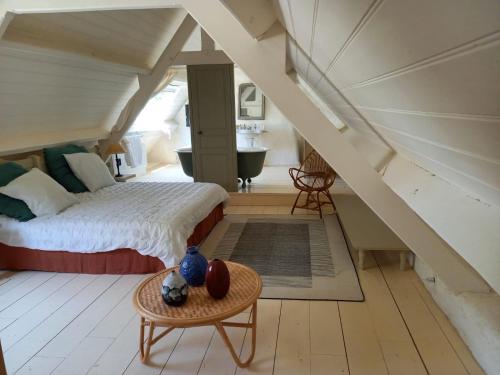 - une chambre mansardée avec un lit et une table dans l'établissement Longere ancienne dans un parc, à Plogonnec
