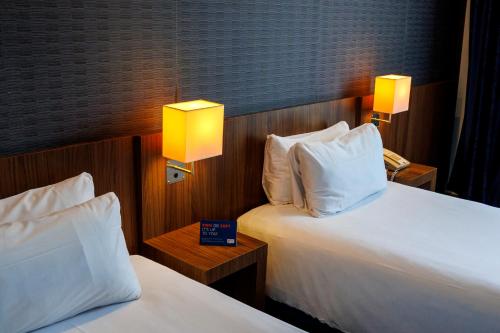 two beds in a hotel room with two lamps at Holiday Inn Express Bilbao Airport by IHG in Derio