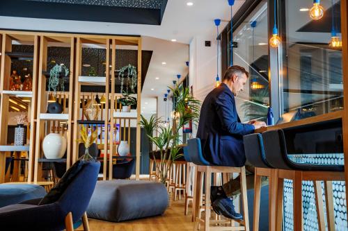a man sitting at a bar using a computer at Holiday Inn Express Bilbao Airport by IHG in Derio