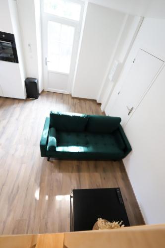 un salon avec un canapé vert et une table dans l'établissement Maison au calme, proche gare & centre-ville, à Brive-la-Gaillarde