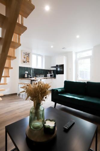 un soggiorno con un divano verde e un tavolo di Maison au calme, proche gare & centre-ville a Brive-la-Gaillarde