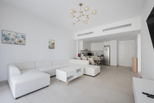 a white living room with a white couch and a table at 1BD Partial Burj Al Arab View Prime Location in Dubai