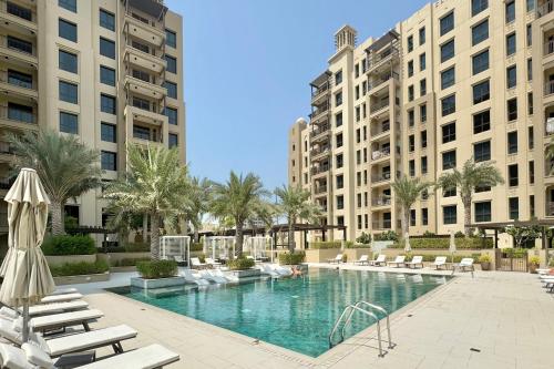 einen Pool mit Liegestühlen und Gebäuden in der Unterkunft 1bd Partial Burj Al Arab View Prime Location in Dubai