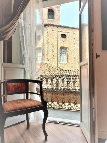 a chair in front of a window with a view at Casa Viaemilia Alessandria in Alessandria