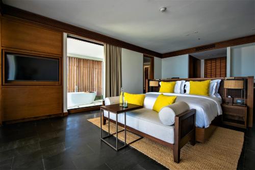 a bedroom with a bed and a tv and a couch at Six Senses Uluwatu in Uluwatu