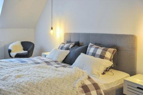 a bedroom with a bed with pillows and a chair at Strict city apartments in Ljubljana