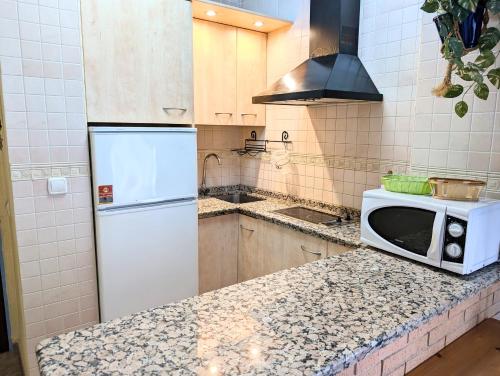 a kitchen with a white refrigerator and a microwave at IslaOC Apartamentos - Apartamento con Acceso Privado a Playa in Isla Cristina