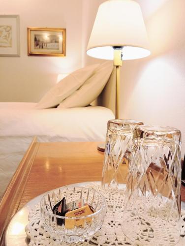 a table with two glasses and a lamp on it at Casa Viaemilia Alessandria in Alessandria
