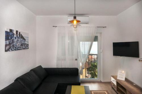 a living room with a black couch and a window at Ellena Sunshine in Opatija