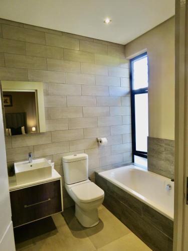 a bathroom with a toilet and a tub and a sink at The Executive - Exclusive Self-Catering Apartments - Ezulwini in Ezulwini