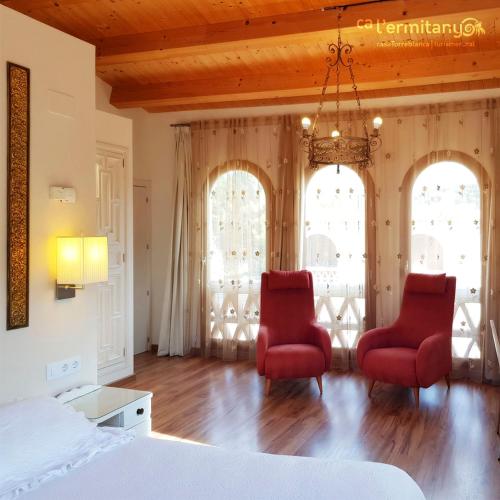 a bedroom with two red chairs and a bed at Ca l' Ermitanyo- Casa Torre Blanca in Suria