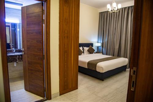 a bedroom with a bed and a door leading to a bathroom at GiNGER LUXURY APARTMENT JUFFAIR in Juffair