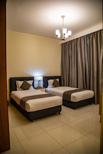 two beds sitting in a room with curtains at GiNGER LUXURY APARTMENT JUFFAIR in Juffair