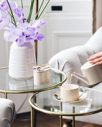 a woman sitting on a couch with a coffee table with cups on it at The Adria in London