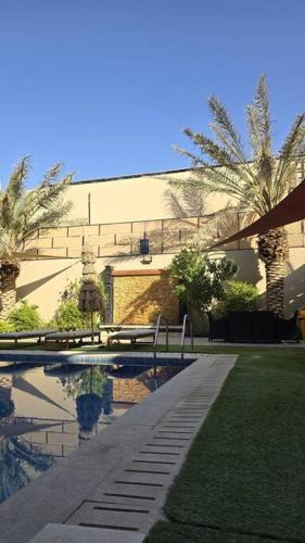 a swimming pool with palm trees and a building at Jumeirah Chalet جميرا شاليه in Amman