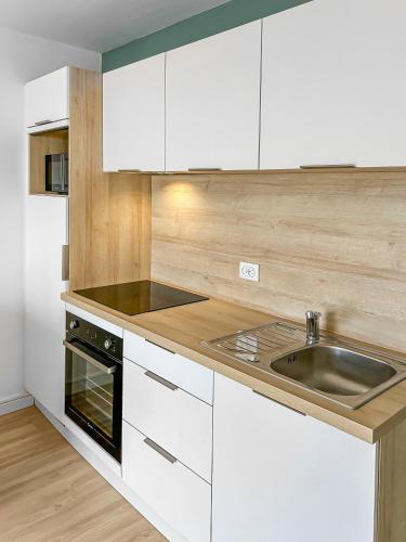 a kitchen with white cabinets and a sink at Le Refuge des Sables in Les Sables-dʼOlonne