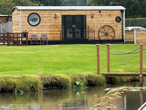 a log cabin with a pond in front of it at Ye Old Lambing Lodge - Spring Paddock in Stafford