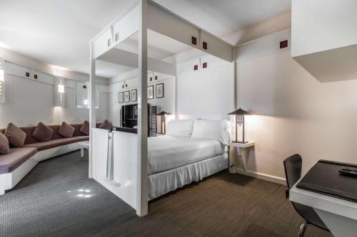 a white room with a bed and a couch at Inn at the Mill, an Ascend Collection Hotel in Fayetteville