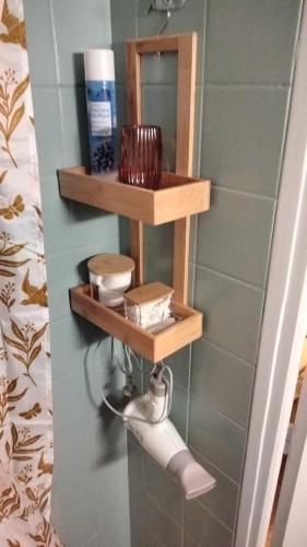 La salle de bains est pourvue d'étagères en bois et d'un rouleau de papier toilette. dans l'établissement Le nid douillet Champêtre Linge fourni, à La Bourboule