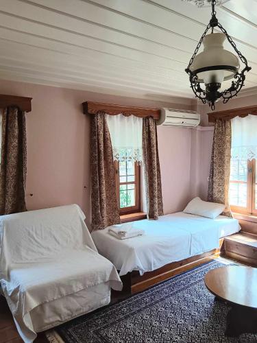 a bedroom with two beds and a table and windows at En Chora Vezitsa in Vitsa