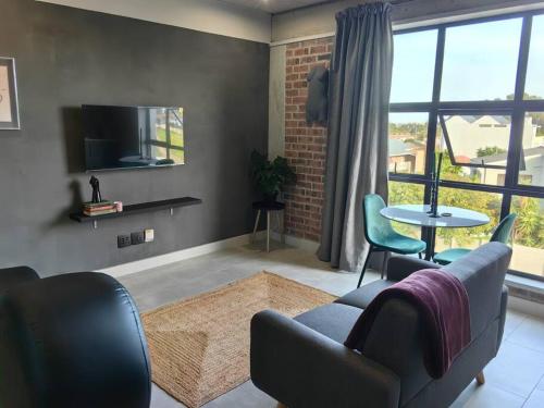 Una sala de estar con un sofá y sillas y un televisor. en Ultra-Modern Studio Apartment, en Table View