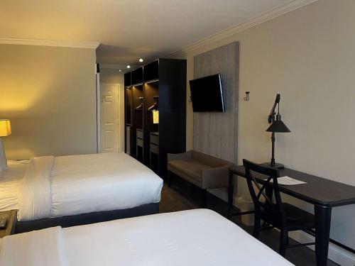 a hotel room with two beds and a table and a desk at The Century House, an Ascend Collection Hotel in Latham
