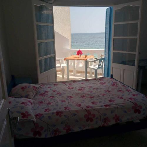 a bedroom with a bed and a view of the ocean at Pied dans l'eau avec balcon in Chott Meriem