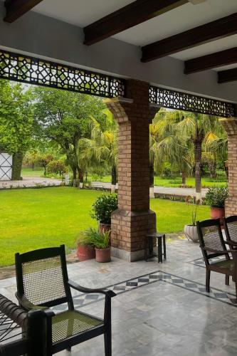 a patio with two chairs and a brick wall at Cozy Farmhouse Retreat in Mardan