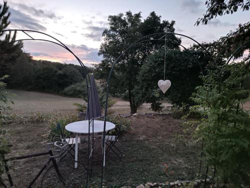 a garden with a table and a heart swing at Une escale gourmande in Eyzerac