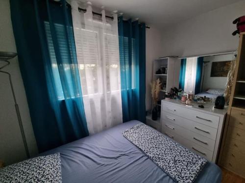 Cette chambre comprend un lit avec des rideaux bleus et une commode. dans l'établissement Comme chez vous, à Villeurbanne