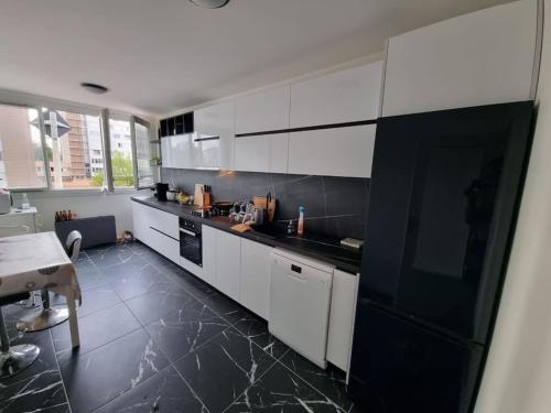 une cuisine avec des armoires blanches et des comptoirs noirs dans l'établissement Comme chez vous, à Villeurbanne