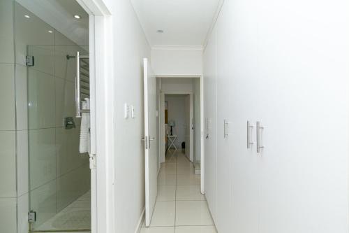 a bathroom with white walls and a walk in shower at Modern Seaview Apartment in Summerstrand