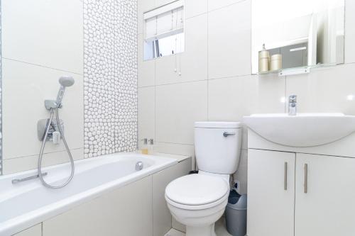 a white bathroom with a toilet and a sink at Modern Seaview Apartment in Summerstrand