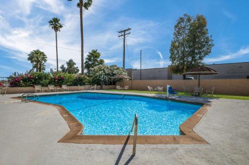 a large swimming pool with chairs and an umbrella at Rodeway Inn & Suites Blythe I-10 in Blythe