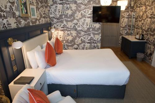a bedroom with a bed with orange pillows and a tv at Henrietta House, a member of Radisson Individuals in Bath