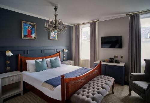 a bedroom with a bed and a chair and a chandelier at Henrietta House, a member of Radisson Individuals in Bath