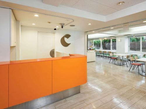 an office lobby with an orange counter and tables and chairs at Comfort Inn Sano Fujioka Inter in Sano