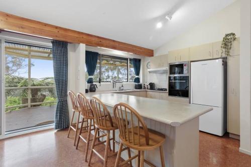 a kitchen with a island with chairs and a counter top at Azimuth - Spacious Family Retreat with City Views in Wentworth Falls