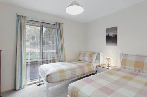 a bedroom with two beds and a window at Azimuth - Spacious Family Retreat with City Views in Wentworth Falls