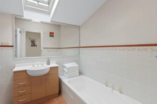 a white bathroom with a sink and a mirror at Azimuth - Spacious Family Retreat with City Views in Wentworth Falls