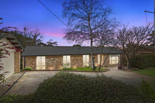 a brick house with a tree in front of it at Azimuth - Spacious Family Retreat with City Views in Wentworth Falls