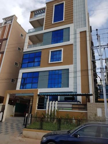 a building with blue windows and a car parked in front at Melody 2 Bedroom Apartment in Hyderabad in Hyderabad