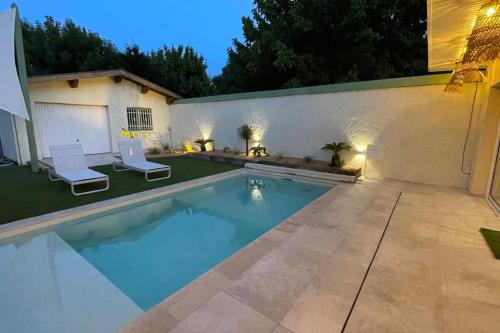 - une piscine dans un jardin avec 2 chaises blanches dans l'établissement Maison en pierre avec sa piscine chauffée, à Le Bouscat